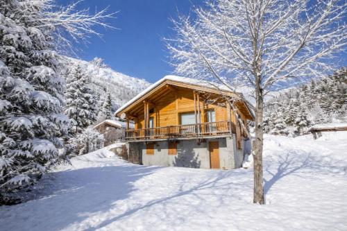 una baita di tronchi nella neve con un albero di Chalet Beugeant - Happy Rentals a Chamonix-Mont-Blanc