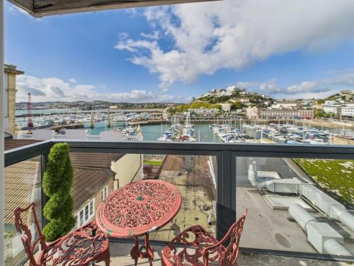 een balkon met een tafel en stoelen en een jachthaven bij The Boathouse in Torquay