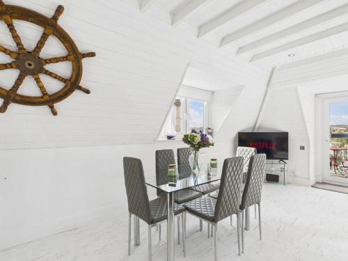 een eetkamer met een tafel en stoelen en een wiel aan de muur bij The Boathouse in Torquay