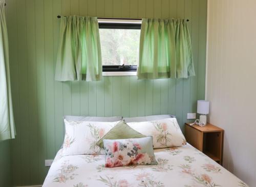 a bedroom with a bed with green walls and a window at The Glan Devon Tiny Retreat in Glan Devon