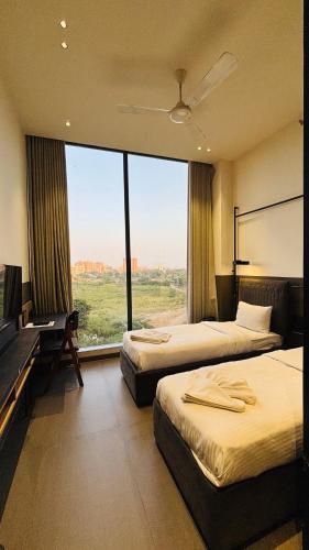a hotel room with two beds and a large window at Ibiza Hotel in Ahmedabad