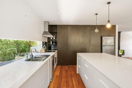 een keuken met een wit aanrecht en een wastafel bij Barramundi Beach House in Smiths Beach