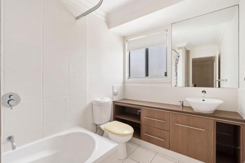 een badkamer met een wastafel, een toilet en een spiegel bij Caba Coast Retreat in Cabarita Beach