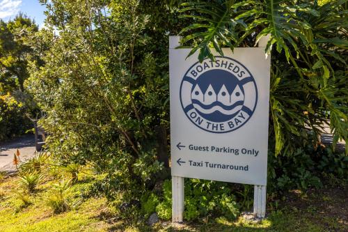 een bord voor een park aan de zijkant van een boom bij Boatsheds on the Bay, Waiheke Island in Ostend