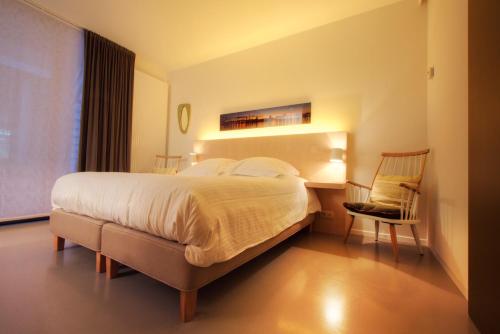 um quarto de hotel com uma cama grande e uma cadeira em Antwerp For Two B&B em Antuérpia
