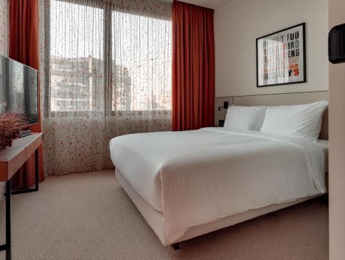a bedroom with a large white bed and a large window at rõõm collective in Odiongan