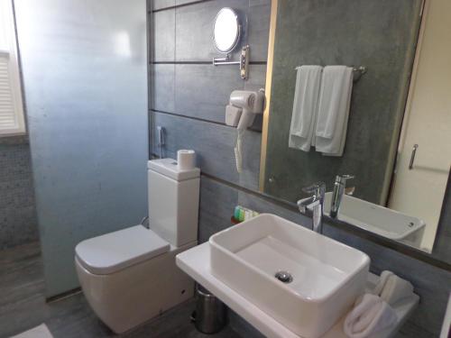 a bathroom with a sink and a toilet and a mirror at South Lake Resort Koggala in Koggala