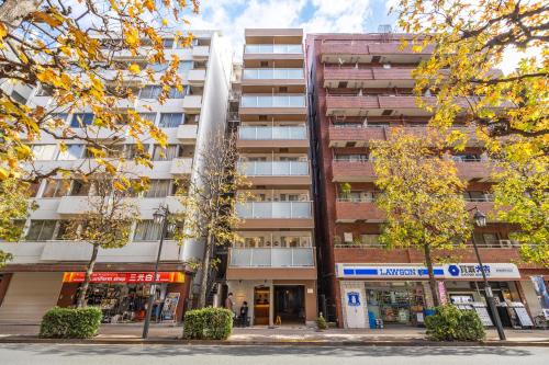an apartment building on a city street with trees at Dash Living Shinjuku in Tokyo