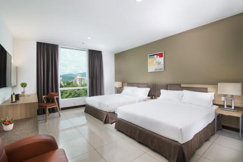 a hotel room with two beds and a window at One Pacific Hotel and Serviced Apartments in George Town