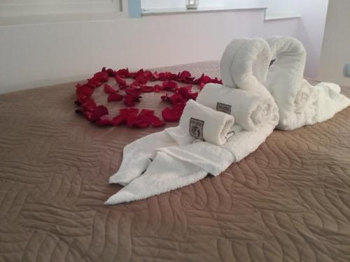 a bed with white towels and a heart made out of roses at Villa Eden Home Holiday in Santa Margherita di Pula