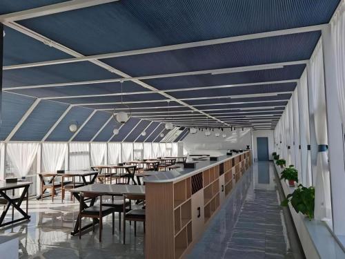 a cafeteria with tables and chairs and a blue ceiling at GreenTree Inn Express Liaoning Jinzhou Bijia Mountain in Dandong