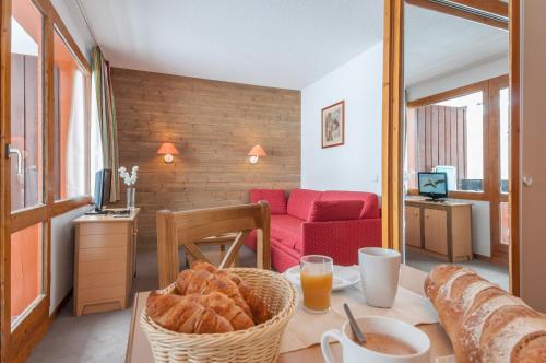 a living room with a table with a basket of bread at Residence Les Chalets des Arolles - maeva Home in Mâcot La Plagne