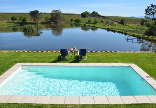 a large swimming pool in front of a large lake at Under Oaks Guesthouse in Paarl