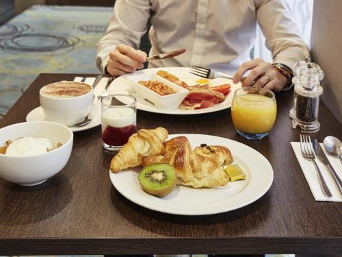 a person sitting at a table with two plates of food at Novotel Coventry in Coventry