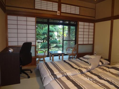 a bedroom with a bed and a desk and a window at Mokkoan in Tokyo
