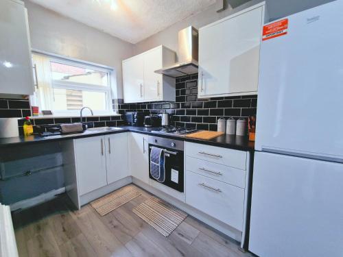 eine Küche mit weißen Schränken und einem weißen Kühlschrank in der Unterkunft Stylish Modern Home comfy setting by Everton Park in Liverpool