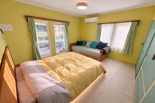 a bedroom with a bed and a couch and windows at ベースクラウン プライベート温泉付き ペット可 in Shiraoi