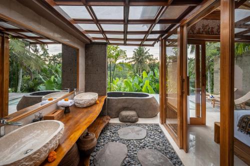 een badkamer met 2 wastafels en een bad bij Govala Usada Ubud Villa in Ubud