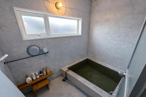 a bath tub in a bathroom with a window at ベースクラウン プライベート温泉付き ペット可 in Shiraoi
