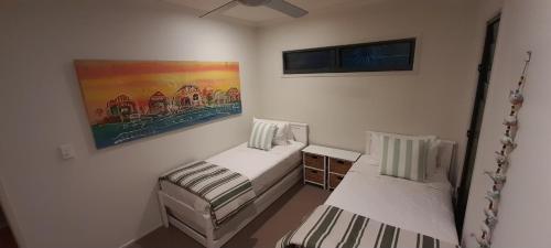 een slaapkamer met twee bedden en een schilderij aan de muur bij Melaleuca Lookout - Pet Friendly in Point Lookout