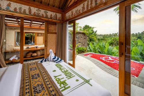 een slaapkamer met een bed en een groot raam bij Govala Usada Ubud Villa in Ubud