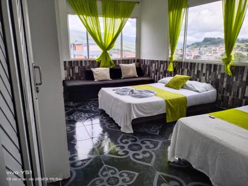 a room with two beds and a couch and windows at Hotel Luis Ángel in Mocoa