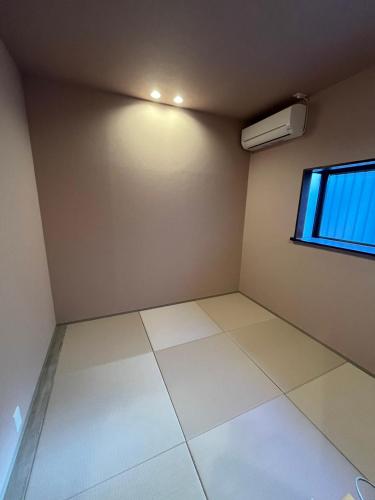 an empty room with a window and white tile floor at BEDandBAR MIDUKI ホステル in Tokyo