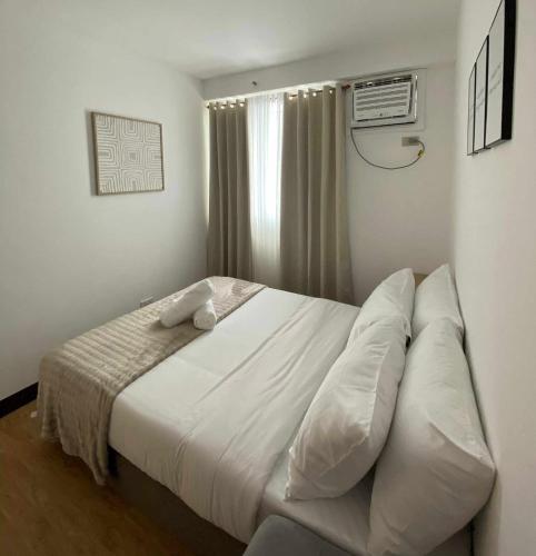 a bedroom with a large bed with white sheets at EasyStay Condo Davao in Davao City