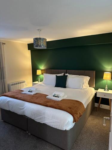 a bedroom with a large bed with a green headboard at Orange Lilly in Stroud with Free Parking in Stroud