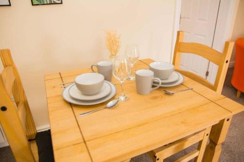ein Holztisch mit Tellern und Weingläsern darauf in der Unterkunft Orange Lilly in Stroud with Free Parking in Stroud
