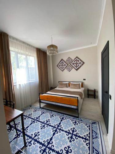 een slaapkamer met een bed en een blauw tapijt bij Ala-Tor Guest House in Pokrovka
