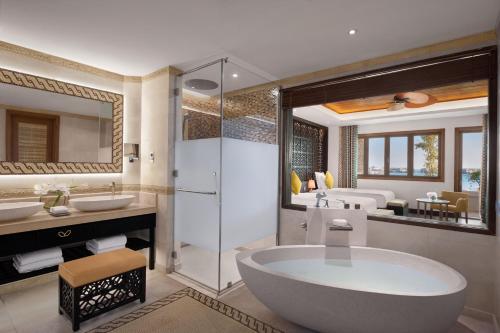 een badkamer met een bad, 2 wastafels en een douche bij Banana Island Resort Doha by Anantara in Doha