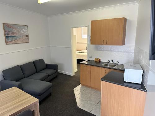een woonkamer met een bank en een keuken bij Bamboo Motor Inn in Lakes Entrance