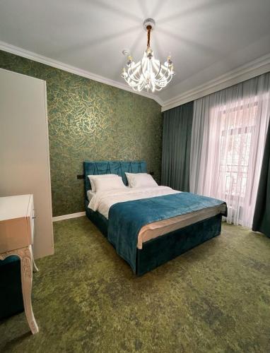 a bedroom with a blue bed and a chandelier at Hilltop Hotel Gusar in Qusar