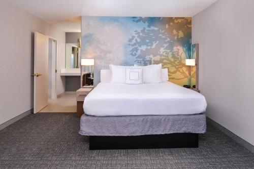 una camera da letto con un grande letto bianco e un dipinto di Country Inn & Suites by Radisson, Brown Deer - Milwaukee North a Brown Deer