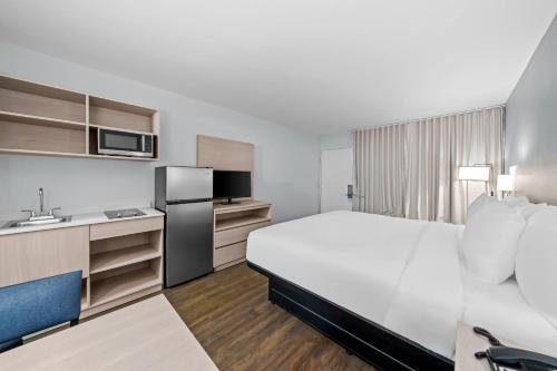 a hotel room with a large bed and a kitchen at Suburban Studios Daytona Beach - Speedway in Daytona Beach