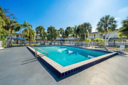 a swimming pool at a resort with palm trees at Suburban Studios Daytona Beach - Speedway in Daytona Beach