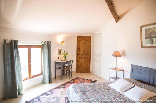 a bedroom with a bed and a table and a window at Campagne de la source St Martin B&B in Cotignac