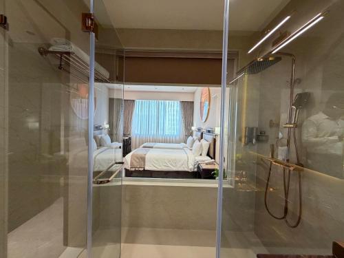 een kamer met een bed en een douche met een glazen deur bij De Lush Pune in Pune