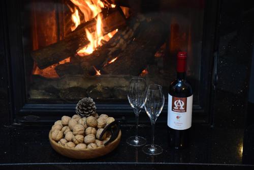 een fles wijn en twee wijnglazen naast een vuur bij Ioni Home in Tsagarada