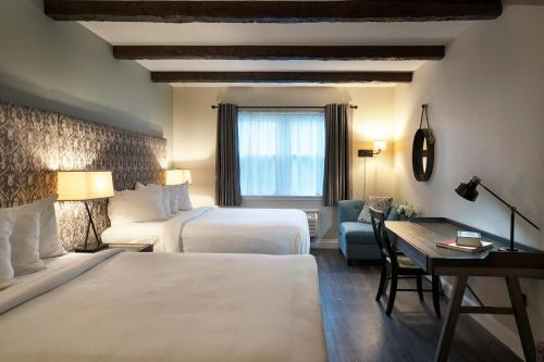 a hotel room with two beds and a desk at The Century House Latham - North Albany, an Ascend Collection Hotel in Latham