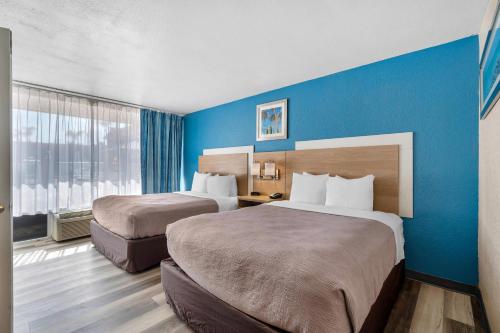 ein Hotelzimmer mit zwei Betten und einer blauen Wand in der Unterkunft Quality Inn & Suites Conference Center in New Port Richey