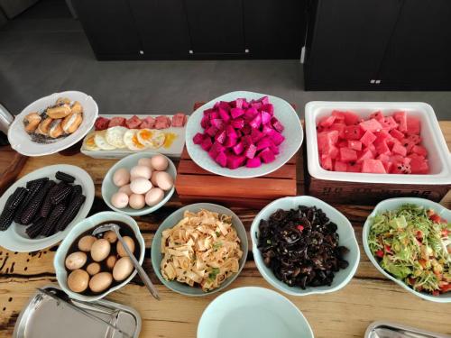 einen Tisch mit Schalen verschiedener Arten von Lebensmitteln in der Unterkunft Xunmiri Qinin Villa in Guiyang