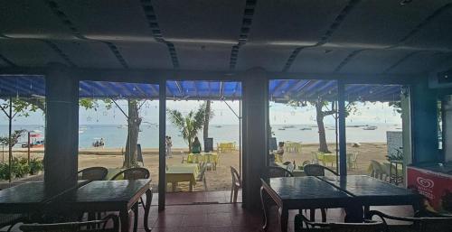 ein Restaurant mit Tischen und Stühlen und der Strand in der Unterkunft Trudis Place Beach Resort and Restaurant in Panglao