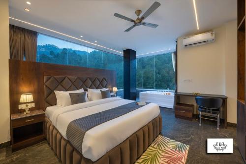 Un dormitorio con una cama grande y una ventana grande. en Blackpearl Sparklewoods, en Kasauli