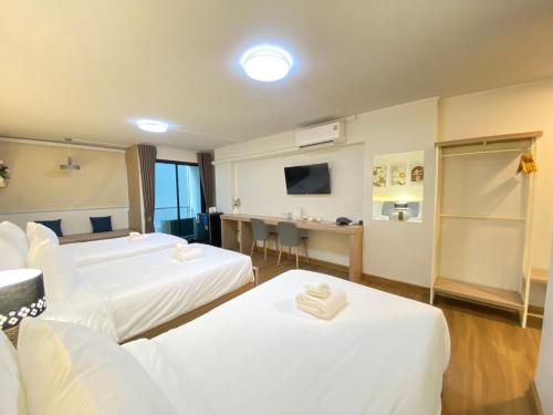 a hotel room with two beds and a desk at Chorbnorn Hotel in Lampang