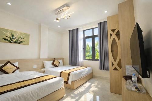 a hotel room with two beds and a window at Lucky Hotel Uông Bí in Uông Bí