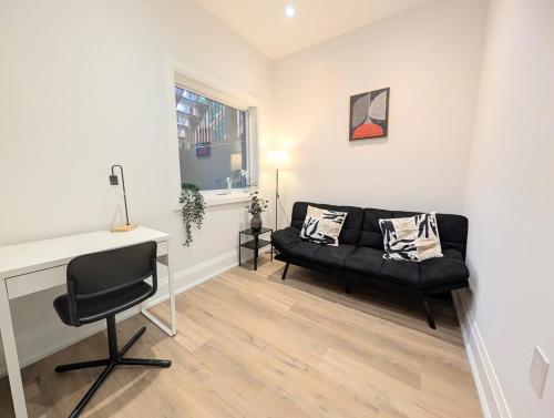 a living room with a black couch and a desk at Luxury 1BR plus den walkout basement in Toronto