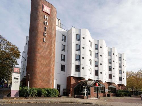a white building with a tall tower next to a street at ibis Portsmouth in Portsmouth