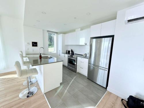 eine Küche mit weißen Schränken und einem Edelstahlkühlschrank in der Unterkunft Luxury Condo with Pool and River View in Baie-Saint-Paul